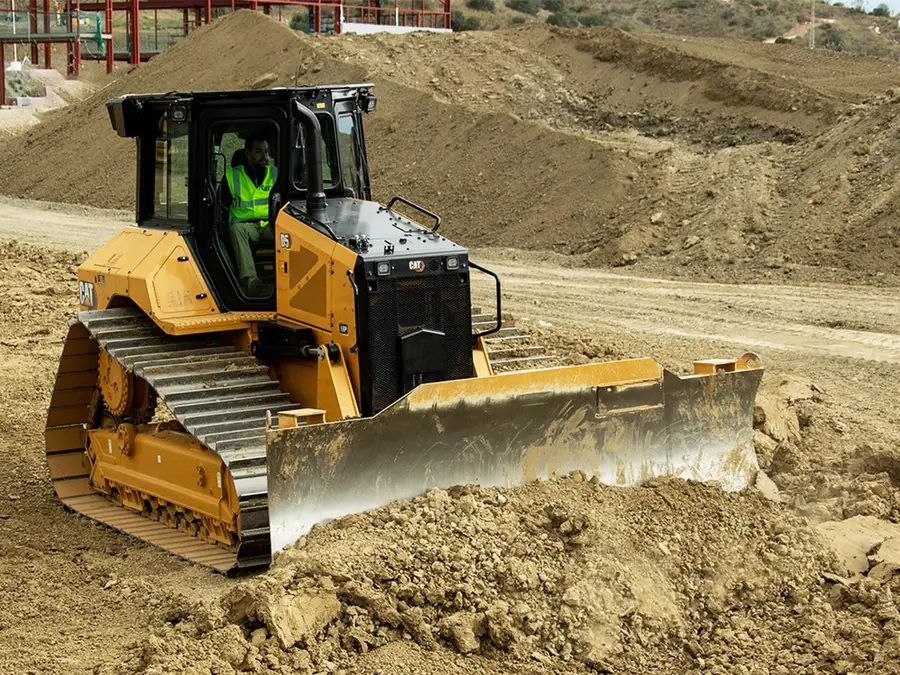 Track loader moving earth across a graded site