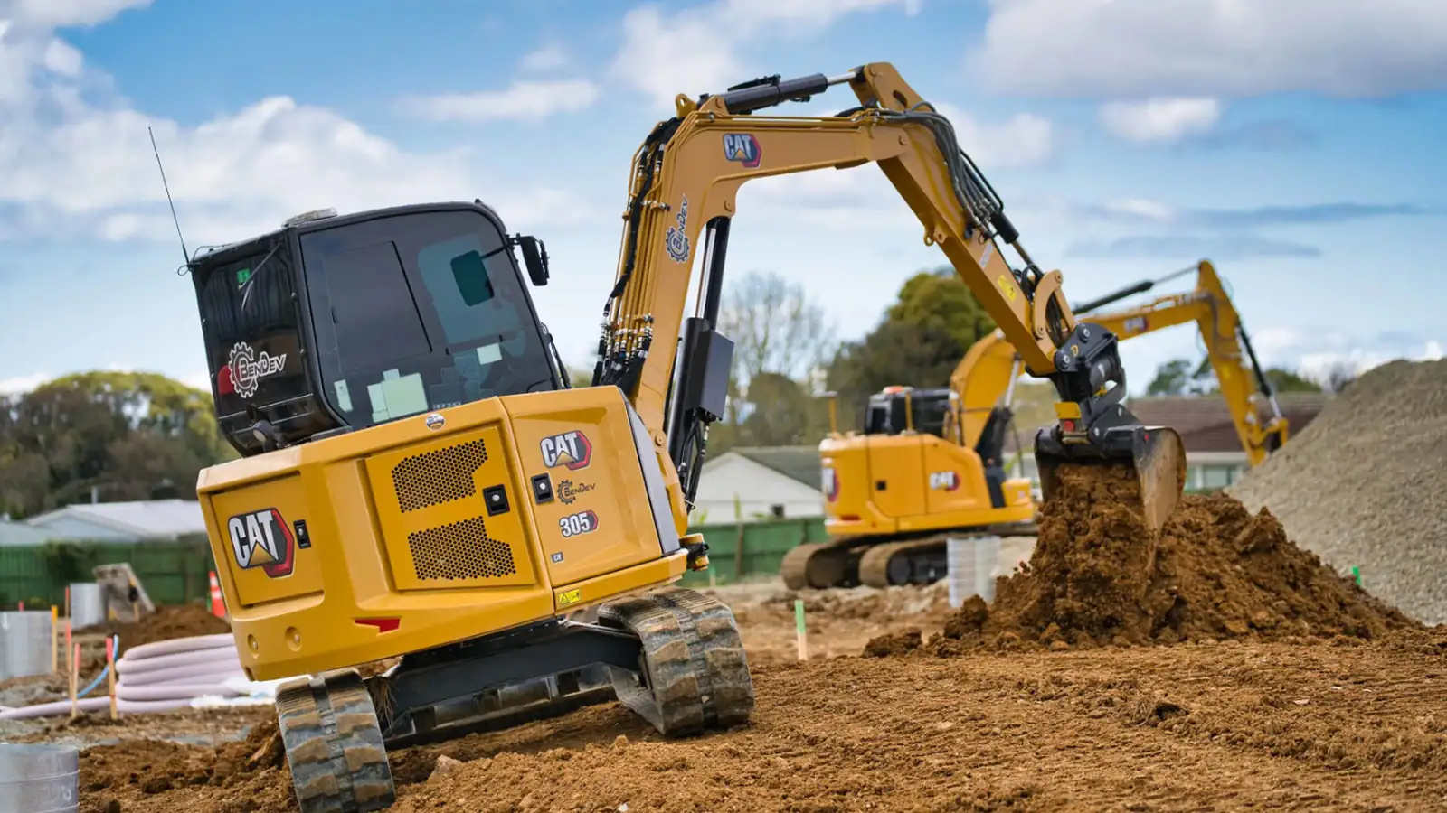 CAT 305 excavators cutting and moving dirt on a residential site